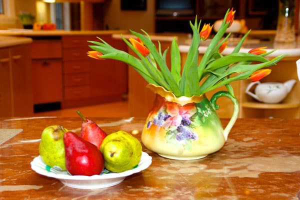 Pops of color in the fruit and flowers enliven this table setting. Creating still lifes with owners’ treasured antiques adds depth to our staging.