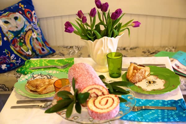 Flowers, food and pillows adorn and soften the look of this wooden kitchen booth.